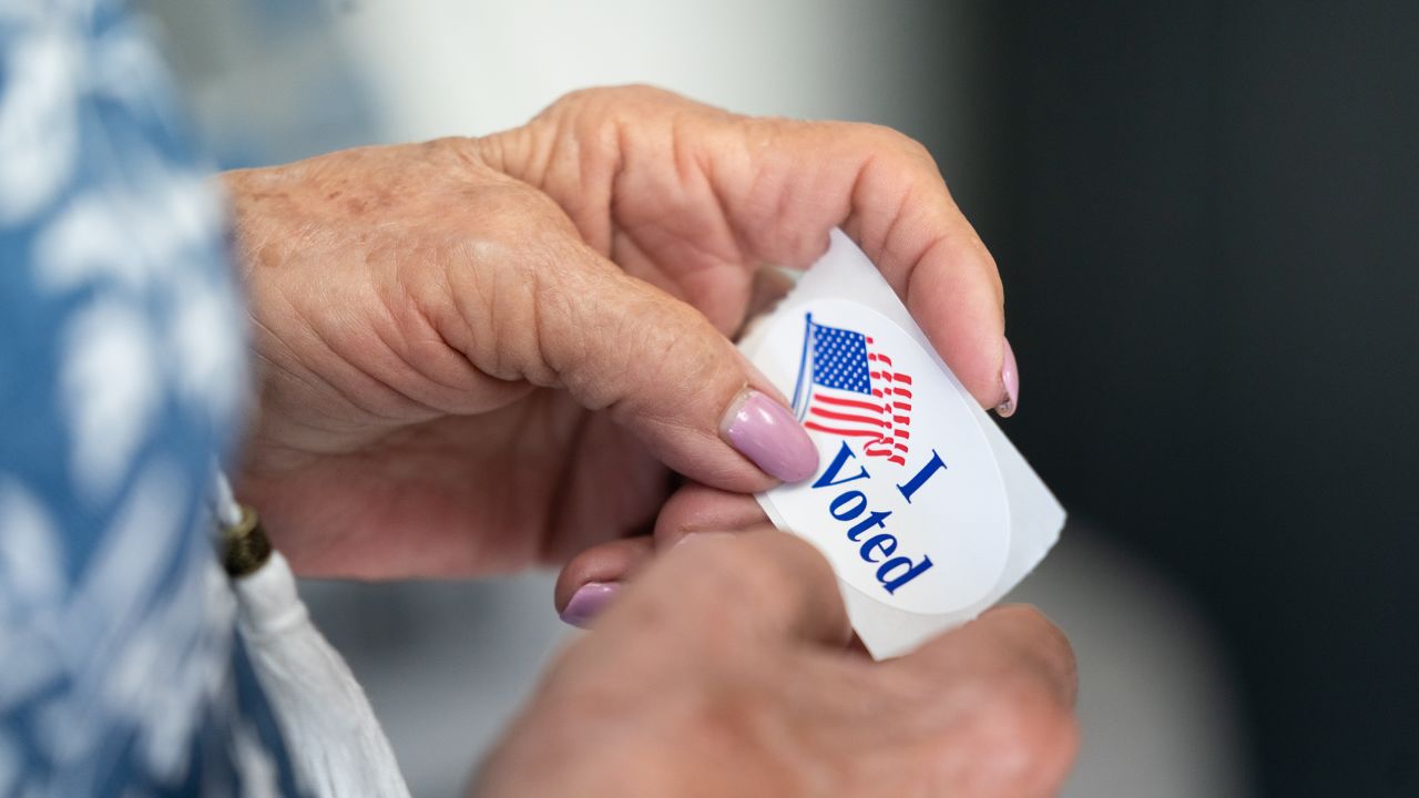 A pair of hands holding an "I Voted" sticker